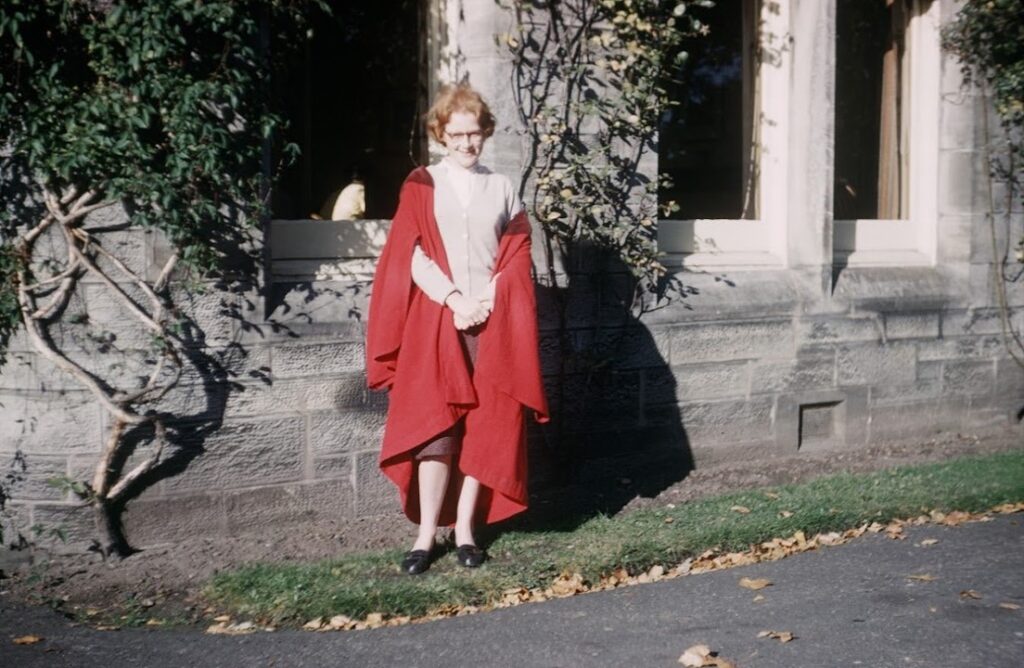 A female student in a red gown, pictured in the 1960s