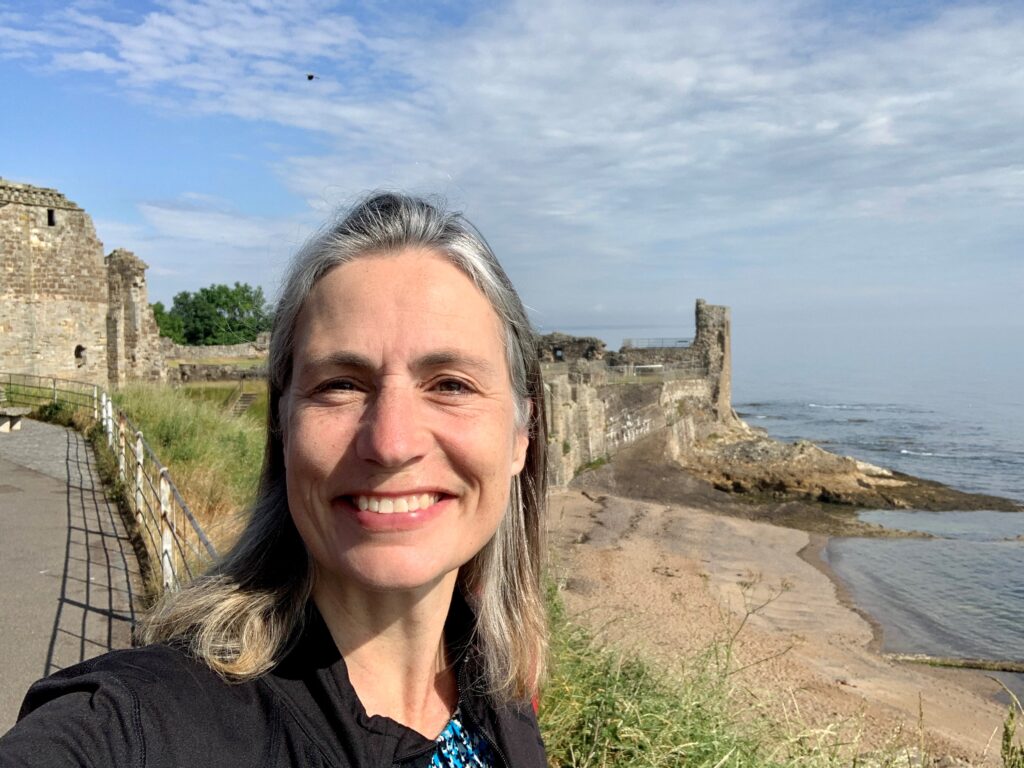 Fiona pictured in front of castle ruins and a beach