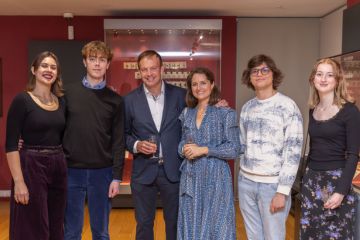 A group photo of six people at a drinks reception