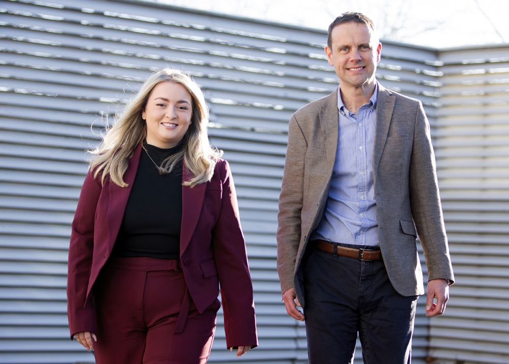 Melissa (left) and Stephen (right) can be seen walking, smiling towards the camera, both are wearing business attire.