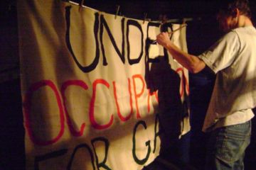 This image was taken in 2009 and shows a university student painting a banner with the words under occupation for Gaza