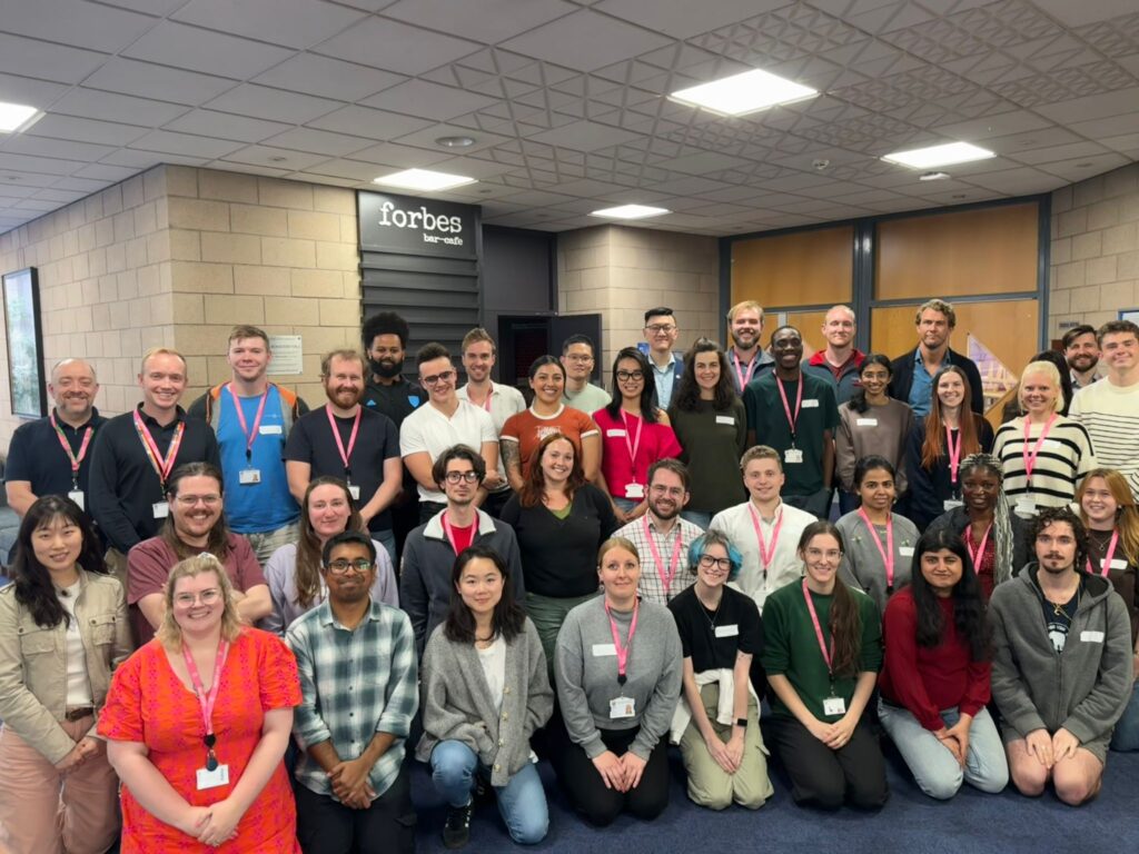 A large group of colleagues are kneeling and standing for a team photo. This is the Halls Life team at the University of St Andrews.