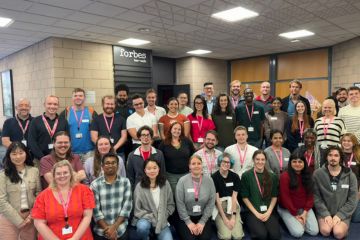 A large group of colleagues are kneeling and standing for a team photo. This is the Halls Life team at the University of St Andrews.