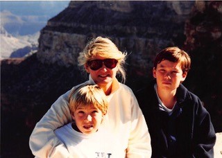 A family photograph featuring two young boys and their mother, who is wearing sunglasses, pictured at the Grand Canyon.