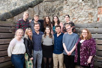 The 2018 charities committee pose smiling for a group photo (five on top row, seven on bottom row). Jessica stands at the bottom centre.