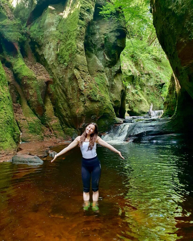 Patricia poses in sportswear standing in ankle-deep water at the Devil's Pulpit