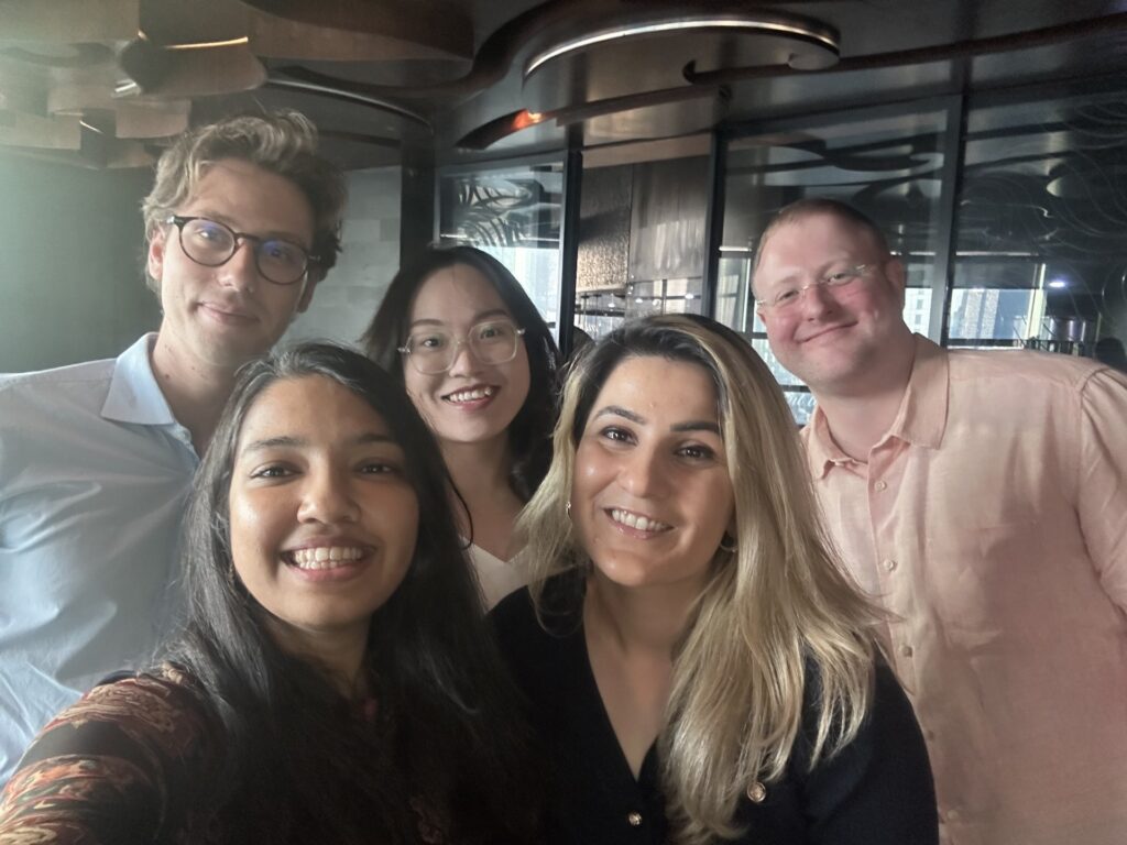 Five alumni pose smiling for a selfie