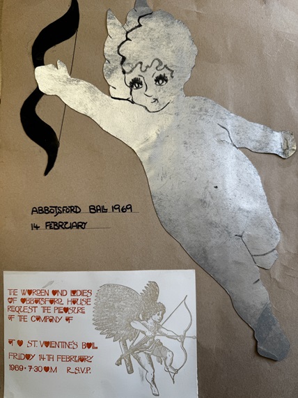 A silver painted cupid shape scrap-booked onto a brown paper sheet, dating from 1969