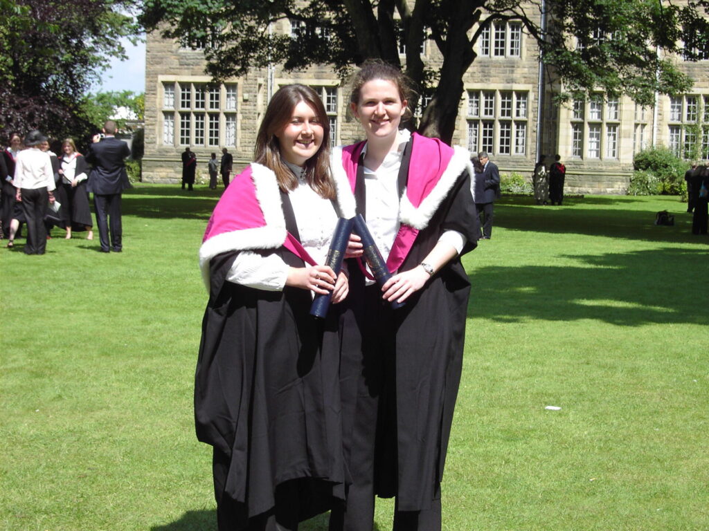 Two female graduates in hoods and gowns