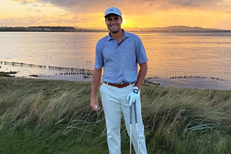 Winston Margaritis standing on the Old Course, St Andrews, at sunset, holding two golf clubs and a ball